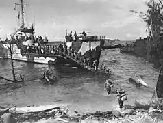 Photo en noir et blanc de soldats débarquant d'un navire sur une plage