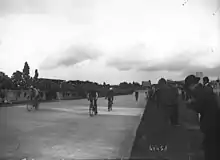 Photographie en noir et blanc montrant des cyclistes sur un vélodrome.