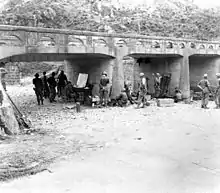 Photo d'un groupe de soldats autour d'un bureaude fortune sous un pont.