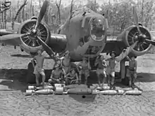 Photographie noir et blanc d'un équipage, sous un bombardier bi-moteur.