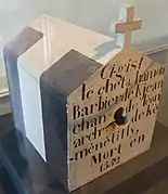 Boîte à crâne en forme de petite maison surmontée d'une croix avec une inscription dessus