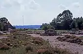 Ruines d'un bâtiment médiéval dans un paysage de plaine.