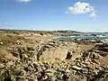 Le littoral entre Fort Bloqué et Le Courégant : falaises basses au premier plan, dunes et plage des Sables rouges au second plan et Le Courégant à l'arrière-plan.