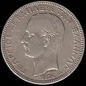 Photographie d'une pièce de monnaie argentée montrant le profil d'un homme moustachu.