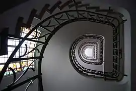 Escalier en spirale avec rampe en fer forgé, permettant d'accéder aux étages de l'immeuble.