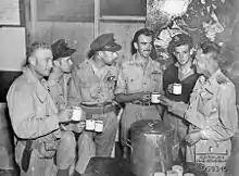 Photographie noir et blanc d'hommes en uniformes, buvant des cafés et discutant.