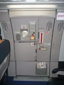 Photographie en couleurs de la porte d'un avion de ligne vue de la carlingue