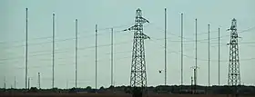 Plusieurs mats d'antenne de grandes taille rapprochées les unes des autres à l'horizon.