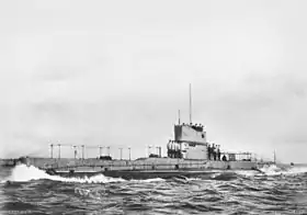 Photographie d'un sous-marin en surface. Plusieurs marins se trouvent sur le pont du submersible.