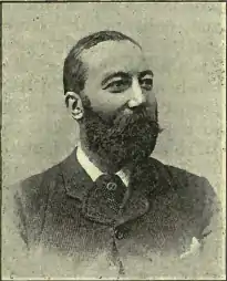 Photographie en noir et blanc en buste d'un homme barbu regardant vers la droite hors du cadre.
