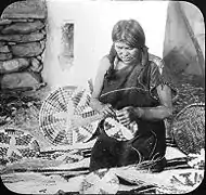 Une femme fabriquant des paniers en 1910.