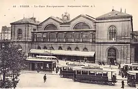 Vue extérieure de la gare. Devant celle-ci, sur la place de Rennes, plusieurs tramways.