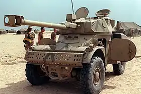 Un véhicule tout-terrain blindé doté d'un canon, immobile, dans un environnement de sable.
