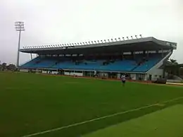 Photographie en couleur d'une partie d'un stade de football et d'une tribune en arrière-plan.