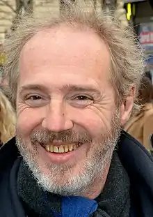 Photographie d'un homme blond souriant.