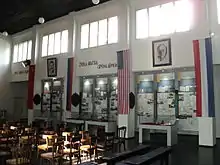 Une salle de réunion transformée en salle d'exposition, avec des souvenirs exposés derrière des vitres et des chaises conservées en l'état. Au mur, des drapeaux alliés (soviétique, russe, américain, néerlandais, ainsi que des portraits de Joseph Staline et Franklin D. Roosevelt.