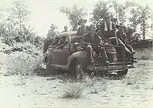 Photographie des soldats assis sur la voiture.