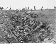 Photographie en noir et blanc d'une tranchée abritant des soldats.