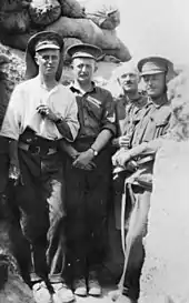 Photographie noir et blanc de quatre hommes en tenue militaire dans une tranchée.