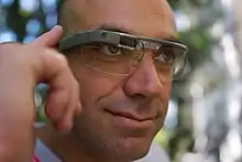 Un homme contrôle des Google Glass, et utilise un touchpad sur le côté de l'appareil.