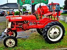 Un tracteur rouge à l'entrée d'un verger.