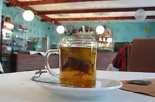 Une tasse en verre avec du thé ; en fond, un décor de restaurant polonais.