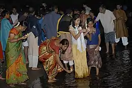 Des jeunes femmes indiennes déposent des lumignons sur l'eau d'une rivière à la tombée du jour