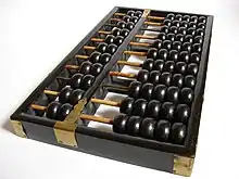 cadre de bois comportant plusieurs tiges parallèles sur lesquelles sont enfilées des boules noires