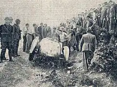 Photo d'un attroupement autour d'une voiture abandonne en bord de piste dans un bas-côté.