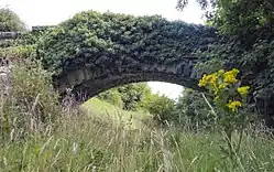 Un pont en pierre à l'abandon franchissant la ligne Otley and Ilkley Joint Railway, fermée en 1965.