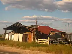 Un bâtiment en bordure de chemin. Le toit est partiellement effondré.