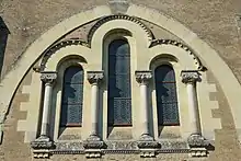 Trois fenêtres hautes et étroites, au sommet arrondi, encadrées de colonnes décorées.