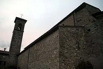 Le flanc d'une église romane dominée par un campanile modeste.