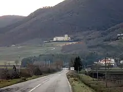 Pente montagneuse couverte d'une végétation méditerranéenne et au milieu de laquelle est située une abbaye de pierre blanche.