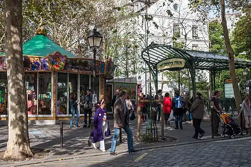 La bouche de métro Abbesses située sur la place est aujourd'hui surmontée d'un des derniers édicules Guimard.