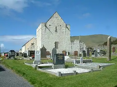 Photographie couleur d'un bâtiment religieux de pierre blanche dans un cimetière.