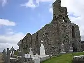 Photographie des ruines d'une église située dans un cimetière.