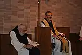 Photographie couleur de deux religieux assis dans un lieu de prière.