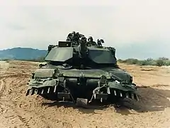 Un M1A1 de l'US Army doté d'une charrue de déminage. Ces griffes ont pour but de pousser les mines en dehors du passage des chenilles.