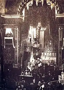 Vue plongeante sur une assemblée dans une cathédrale avec un personnage assis sur un grand trône à baldaquin à gauche de l'autel