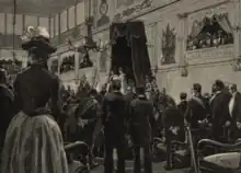 Dans une salle remplie d'hommes en habits élégants, un homme portant une cape d'hermine se trouve sous un dais