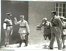 Officier en képi saluant un garde britannique en passant devant lui.