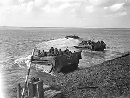 Photographie en noir et blanc de véhicules militaires amphibies embarquant sur l'eau