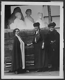 Photographie noir et blanc de la sculptrice Adelaïde Johnson accompagnée de deux femmes, devant son œuvre.