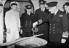 L'amiral Sir Bruce Fraser, commandant en chef de la Home Fleet britannique, verse du rhum dans le mélange pour le Christmas pudding de 1943 à bord du HMS Duke of York (novembre 1943).