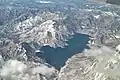 Photo aérienne couleur d'un lac entouré de montagnes enneigées.
