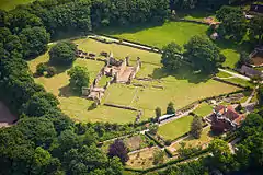 Photographie aérienne des ruines d'un monastère au milieu d'une vaste clairière.