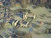 Vue aérienne des ruines gothiques d'une abbaye, à proximité d'un hameau.