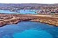 Vue aérienne de l'extrémité occidentale des installations de l'aéroport, avec en arrière-plan le port de la ville de Lampedusa.