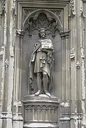 Photo de la statue d'un roi en pied, avec couronne et sceptre, pourtant une église symbole de sa fondation.